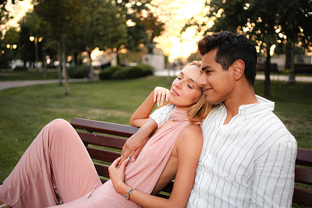 istock Young couple relaxing on a bench in a park at sunset 2232898053
