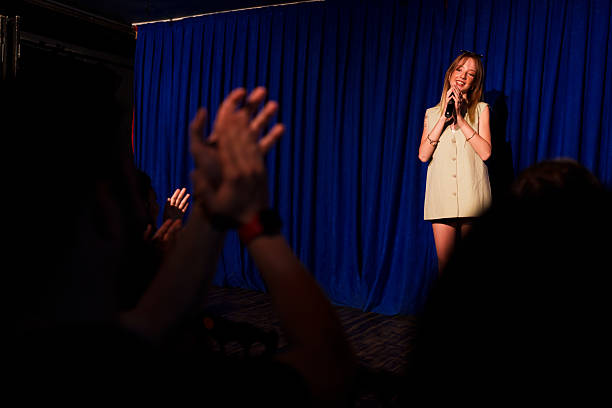 istock Woman performing on stage with microphone in front of audience 2232899232