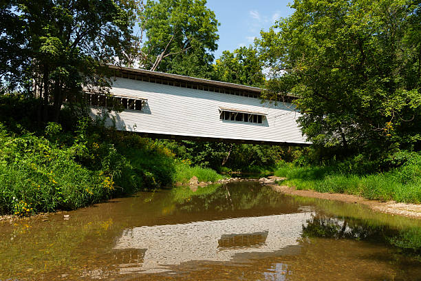 The Oakalla Covered Bridge crosses Big Walnut Creek in Putnam County, Indiana. The covered bridge with bright red weathered siding was built in 1898.