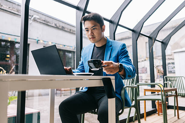 istock Young man working on laptop and enjoying coffee in a modern cafe 2232909599