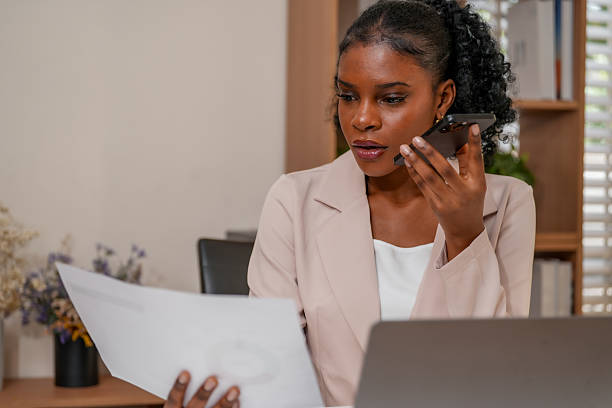 istock Professional woman engages phone conversation while reviewing documents modern office setting. This scene highlights connection between technology and creative collaboration work environment 2232914562