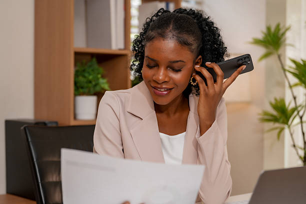 istock Professional woman engages in phone conversation while reviewing documents, showcasing essence of collaboration and connection through technology in creative workspace 2232914592