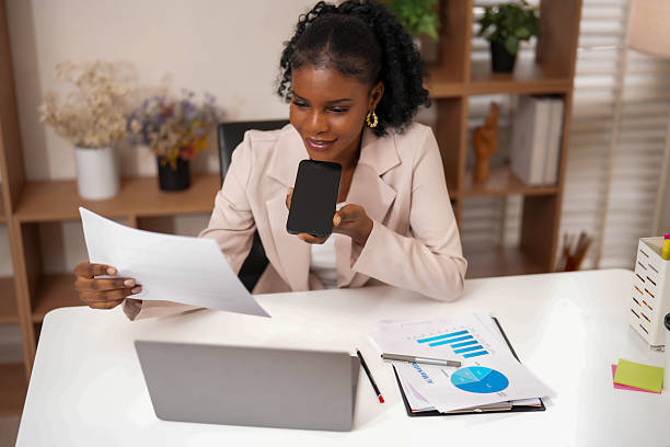 istock Professional woman engages productive work session, utilizing technology to enhance collaboration and connection. She reviews documents while holding smartphone, showcasing creativity her 2232914624