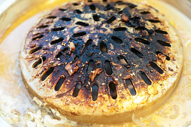 Close-up of a charred cooking surface from a grill, showcasing residue and flavors left from grilling food. Perfect for culinary and barbecue themes.