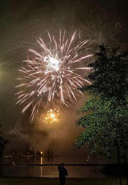 istock Fireworks over the lake. A human silhouette watching the fireworks. 2232914991