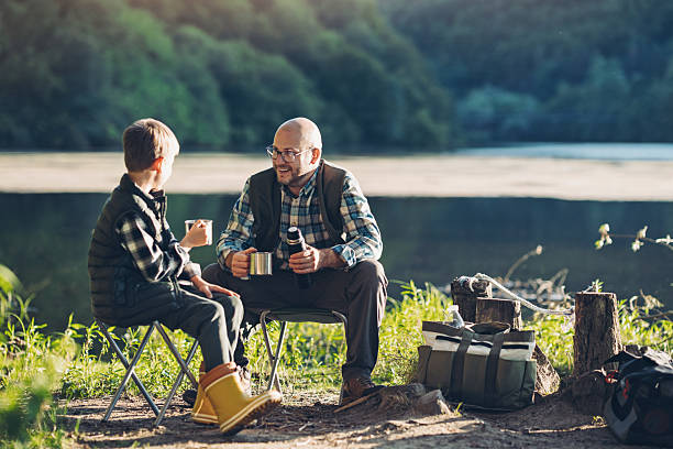 istock Father and son camping by the river drinking tea and resting 2232915547
