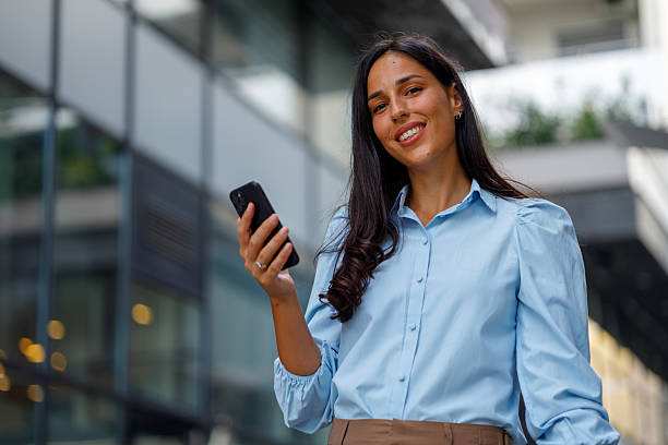 istock Professional female entrepreneur checking smartphone, urban skyline behind, expressing workplace confidence and dynamic career success 2232918647