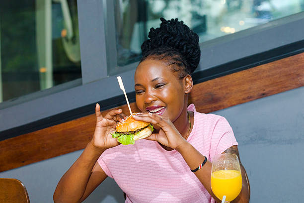 istock Kenyan young woman eating a burger in restaurant 2232919155