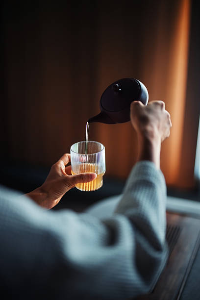 Pouring Hot Tea into a Glass Cup in a Cozy Setting