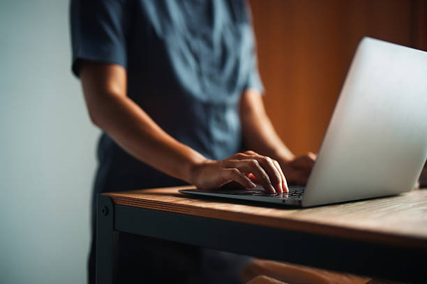 A person typing on a laptop in a modern workspace with ambient light, conveying productivity and focus. The scene showcases technology use in a contemporary working environment.