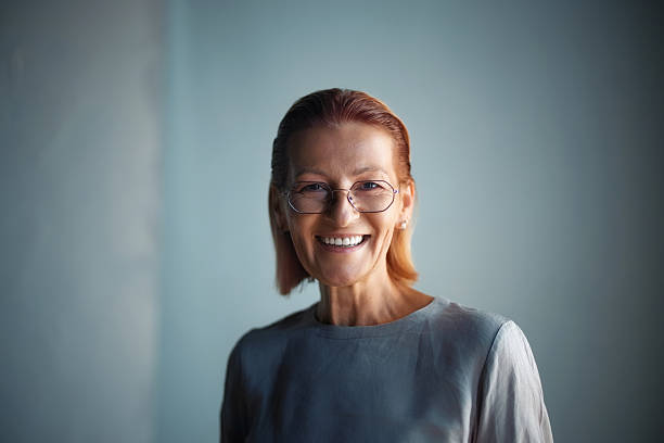 istock Smiling Mature Woman With Glasses Posing in Studio Against Blue Background 2232921164