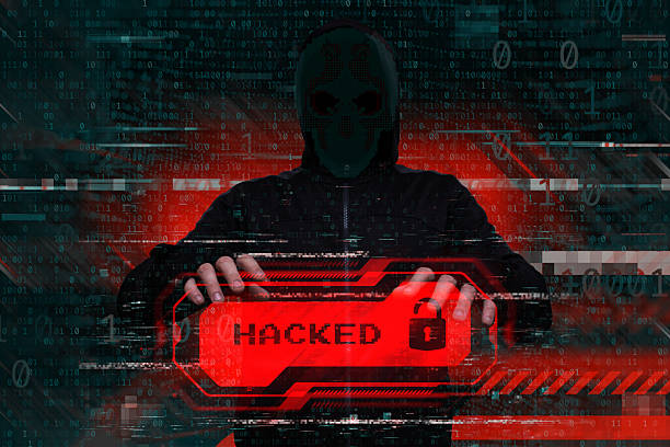 istock Masked hacker behind a computer with a red warning Hacked. Concept of cybersecurity threat, attacks on data and online systems. 2232923605