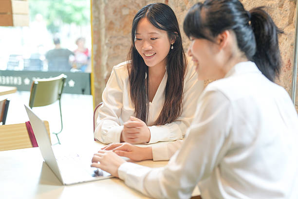 istock Two women are sitting at a table with a laptop in front of them 2232924579