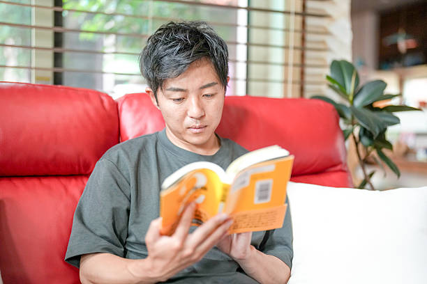 istock A man is reading a book on a red couch 2232928779