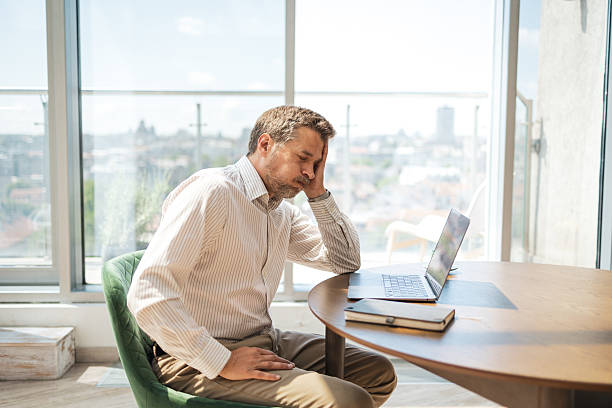 istock Tired man sitting at desk with laptop in modern office space 2232930321
