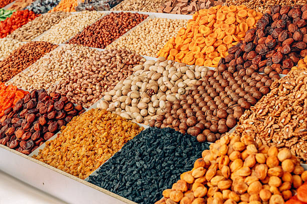 Colorful dried fruits and nuts are displayed in small wooden boxes at a market stall, creating a vibrant and tempting arrangement