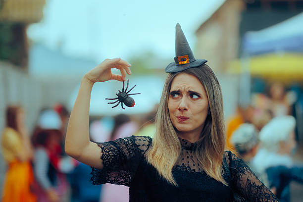 istock Woman in Witch Costume Holding a Spider Decoration Making Grimaces 2232944372