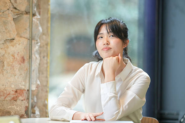 istock A woman is sitting at a table with her hands on her chin 2232953409