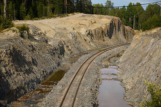 A winding railway track intricately snakes through the rugged terrain, showcasing exposed rock formations and puddles