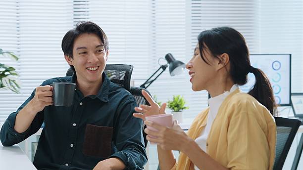istock Two colleagues asian business  having a coffee break in an office sharing a lighthearted moment  relaxing and talking after working time 2232960195