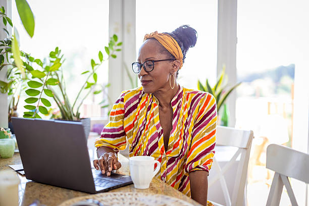 istock Happy woman drinking coffee and using laptop at home 2232960659