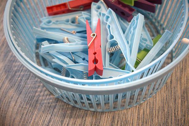 Colorful plastic clothespins inside a blue plastic basket. Close up view.