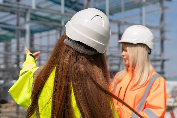 istock Two construction workers in bright safety jackets engage in conversation on a building site 2232962667