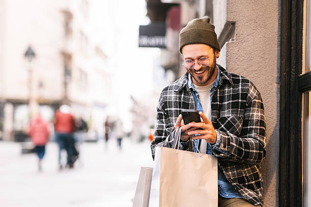 istock Man with shopping bags using smartphone 2232963159