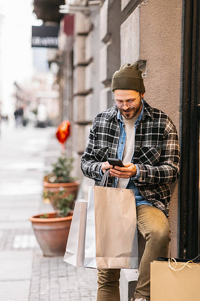 istock Man with shopping bags using smartphone 2232963165