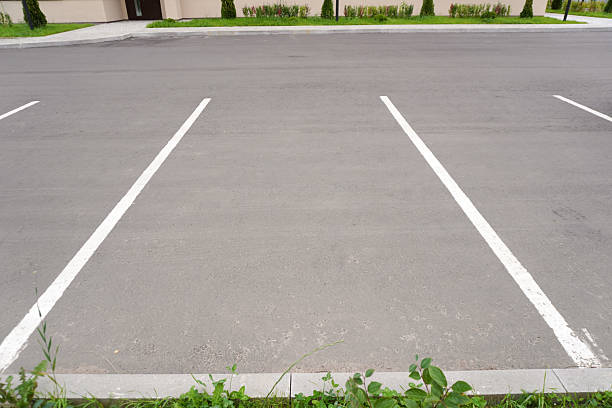istock Empty parking lot spaces showing white lines and green grass 2232963451