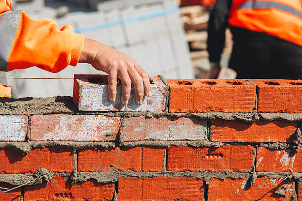 istock Bricklayer laying another brick in the wall on construction site for sturdy wall 2232964317