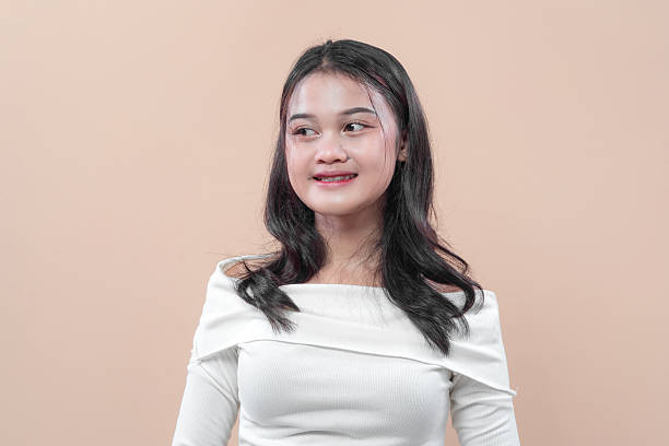istock An Asian woman with long black hair smiling softly while looking sideways, dressed in a white off-shoulder top, showing charm, elegance, and confidence. 2232964574
