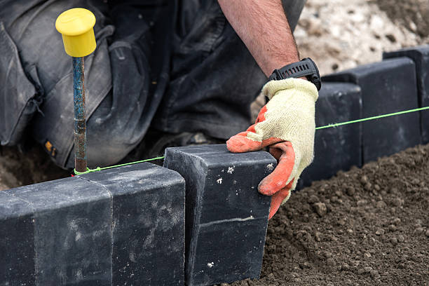 istock Close-up of builder laying black paving bricks on  building site 2232965443