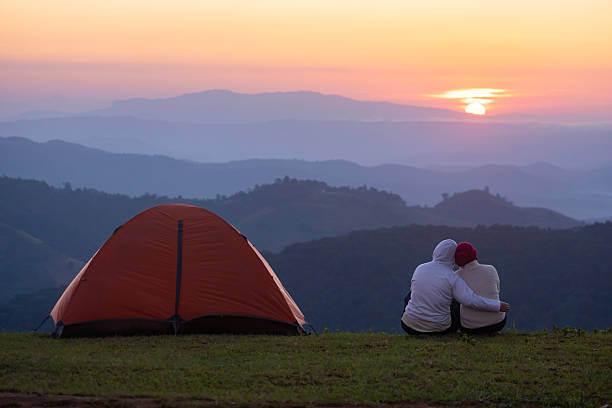 istock Couple is sitting by their tent during overnight camping and hugging while looking at the beautiful scenic sunset over the mountain for outdoor adventure vacation travel 2232966769