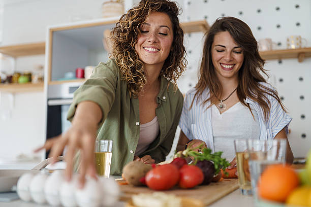 istock Two Young Women Friends Laughing While Preparing Fresh Ingredients In Modern White Kitchen 2232969476