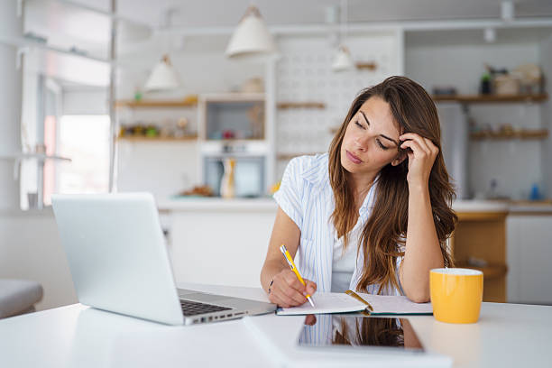 istock Young Woman Working Remotely in Stylish Apartment with Laptop and Notebook 2232970895