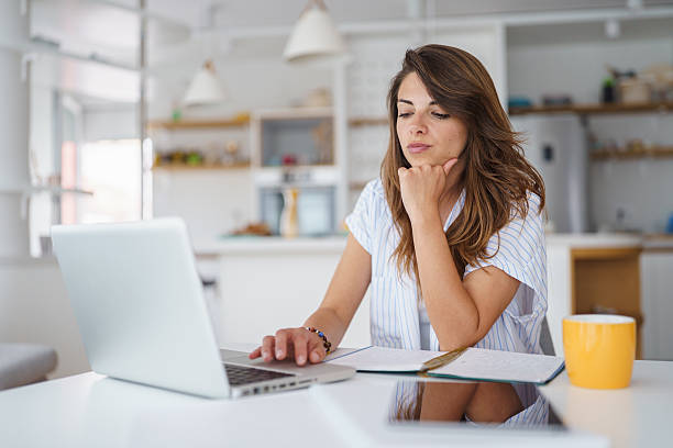 istock Young Woman Working Remotely in Stylish Bright Apartment Using Laptop and Notepad 2232970905