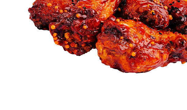 Crispy chicken wings coated in spicy sauce on a white background
