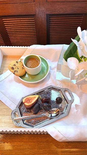 istock Silver tray displaying morning delicacy, steaming coffee, chocolate chip cookie, ripe figs, grapes, complemented by delicate white floral arrangement 2232973483
