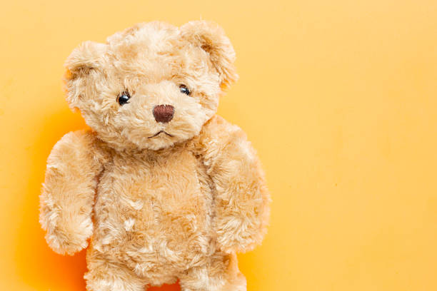 istock Cute brown teddy bear plush toy on orange background. 2232976120