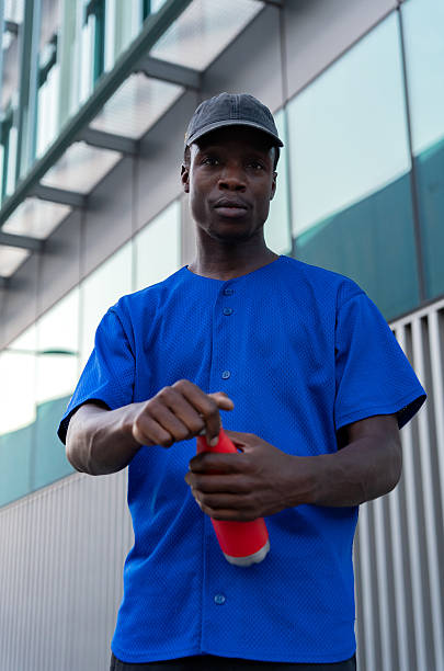 istock Urban scene showing young African American male opening red bottle, drinking refreshment while standing outdoors on bright summer day 2232978708