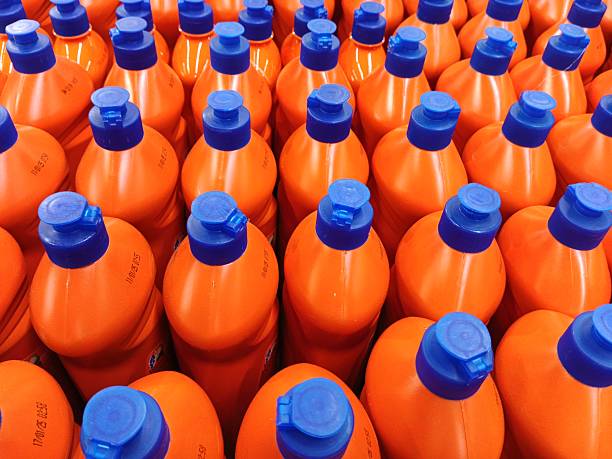 White plastic bottles of laundry detergent neatly arranged on a shelf.