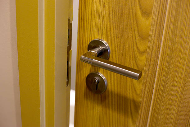 istock Wooden door with modern stainless steel handle and lock, slightly open 2232979732