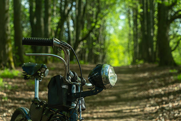 istock Closeup of vintage bicycle headlight with blurred forest background and soft natural light. Old bicycle resting on a sunlit woodland path symbolizing outdoor adventure and eco friendly travel. 2232980351