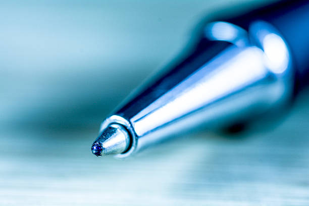 Extreme close-up of a ballpoint pen tip, showing fine details of the writing instrument's metal surface and precision