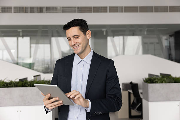 istock Businessman in suit standing in office working on digital tablet 2232987480