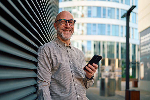 istock Smiling businessman using smartphone in front of office building 2232988912