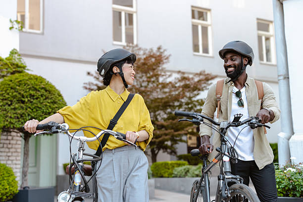 istock Two individuals walking with bicycles through a green downtown area 2232991698