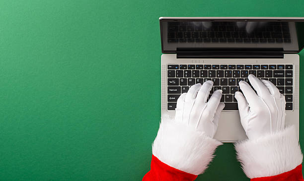 Santa Claus typing on a modern laptop, emphasizing Christmas and technology synergy