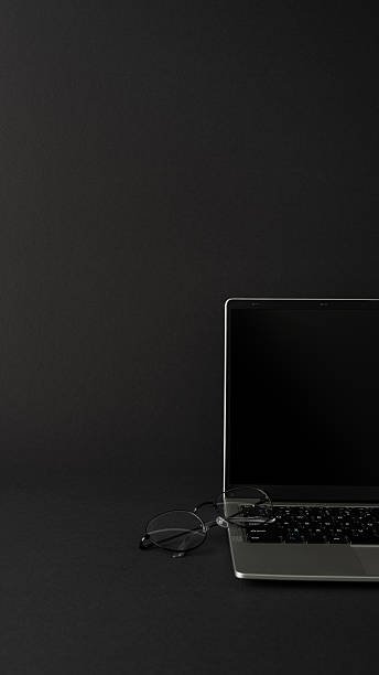 istock Laptop with a vertical blank screen partially visible, eyeglasses resting on the keyboard 2232991966